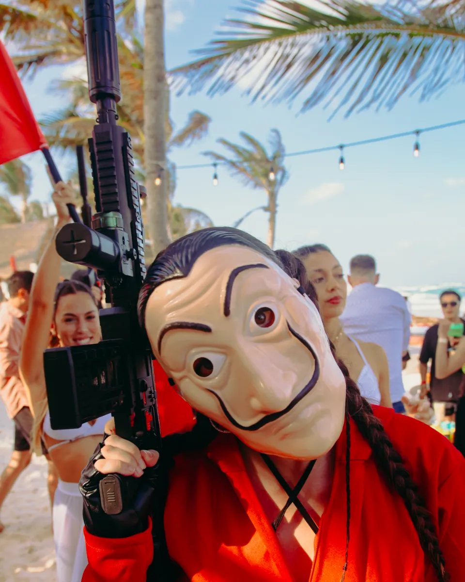 Persona con m&aacute;scara y rifle en una fiesta en la playa.