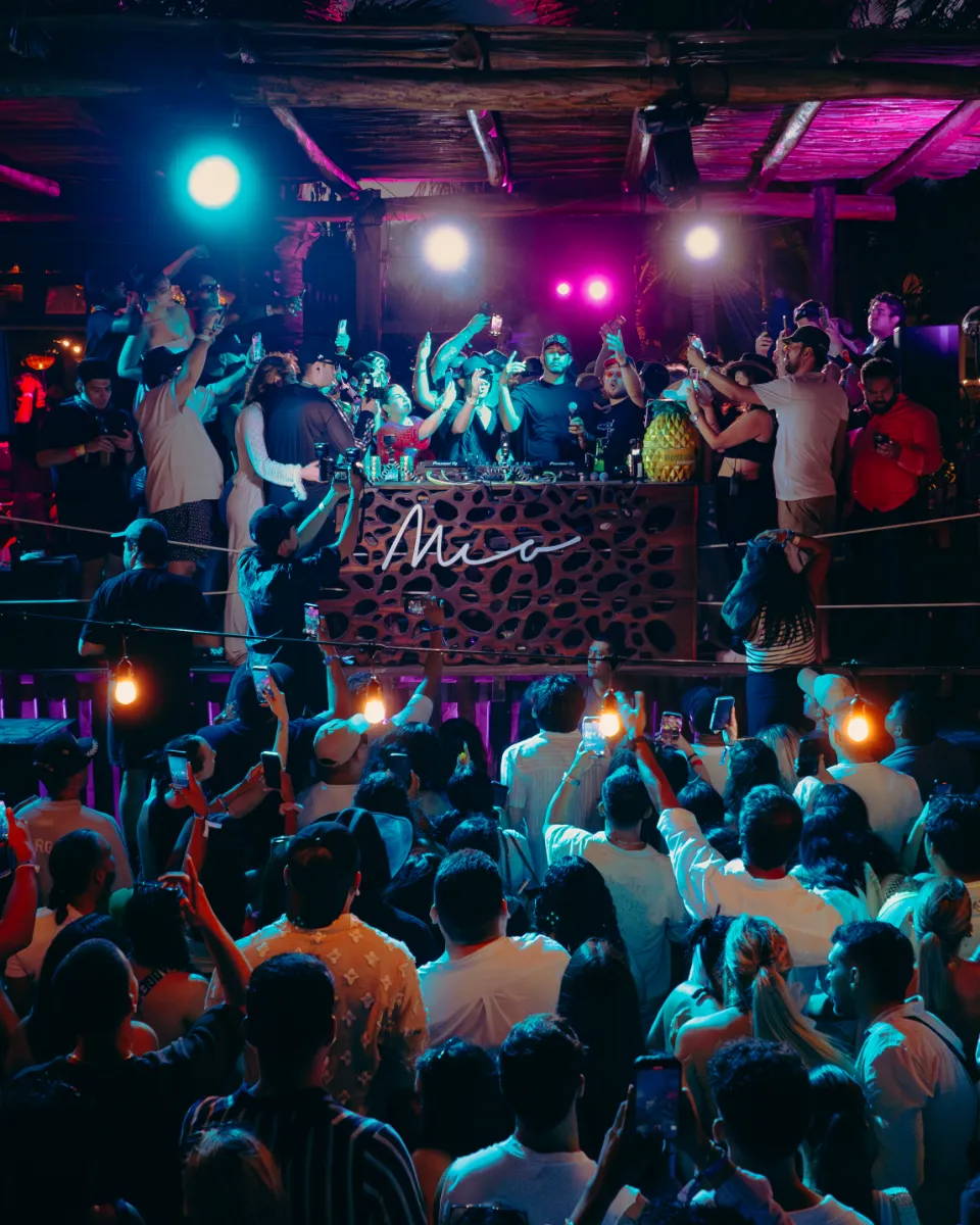Grupo de personas disfrutando en una discoteca iluminada con luces de colores.
