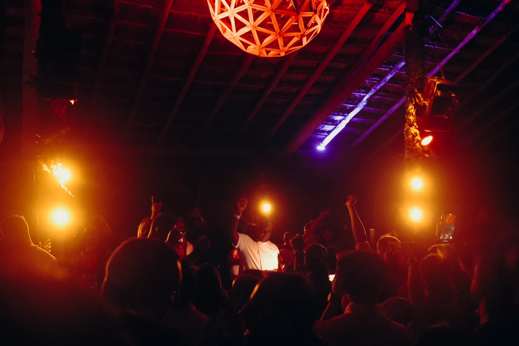 Fiesta nocturna con luces cálidas y personas celebrando bajo techo.