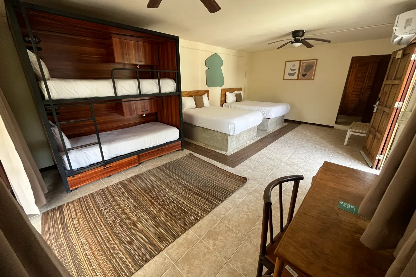 Habitación con camarotes de madera, dos camas dobles y un pequeño escritorio.