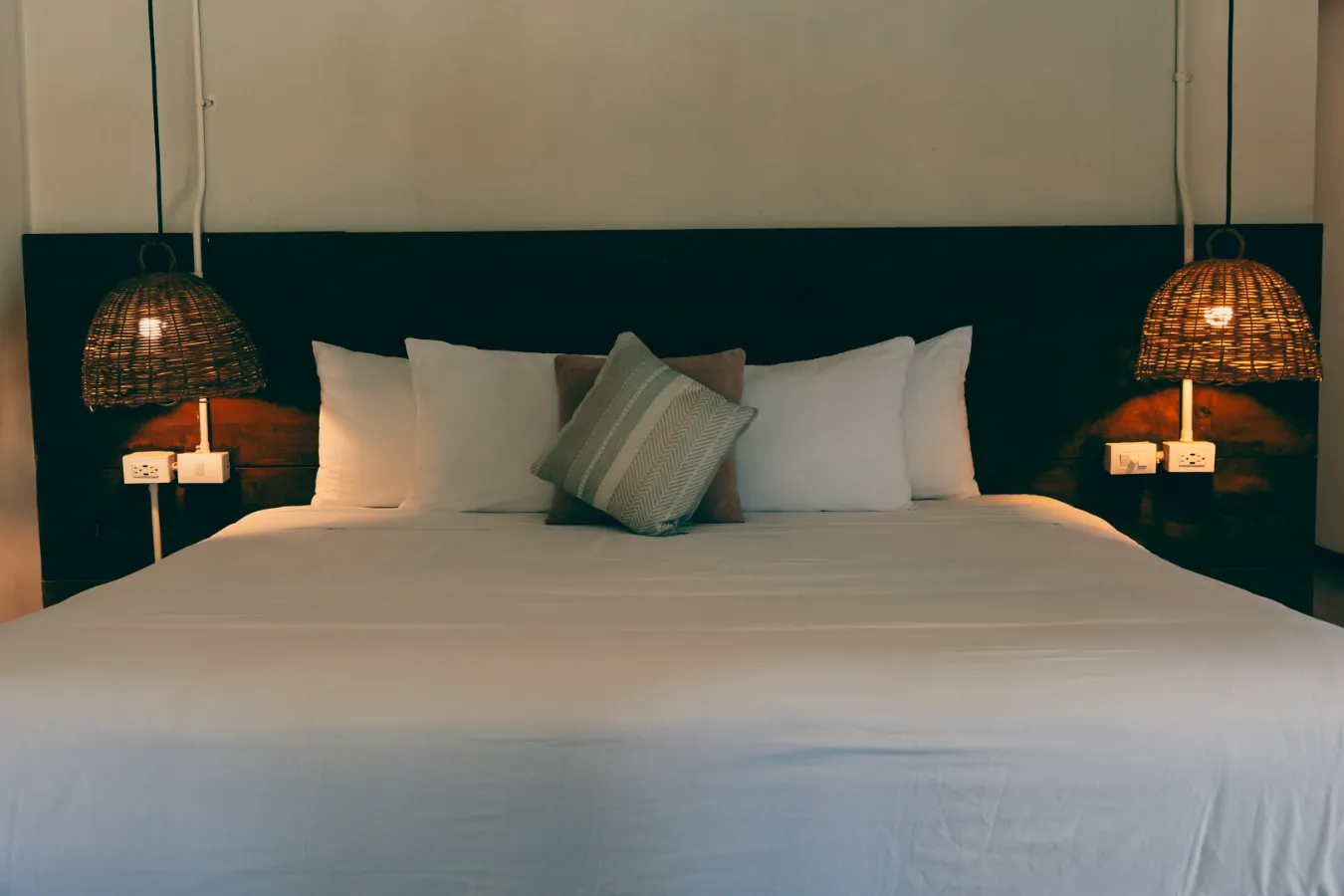 Cama con cojines y lámparas colgantes a cada lado.