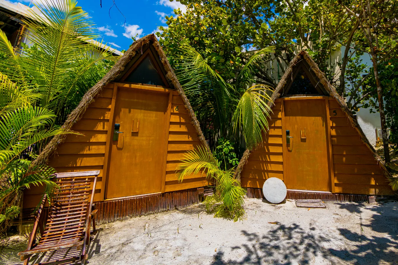 Cabañas triangulares de madera rodeadas de vegetación tropical.
