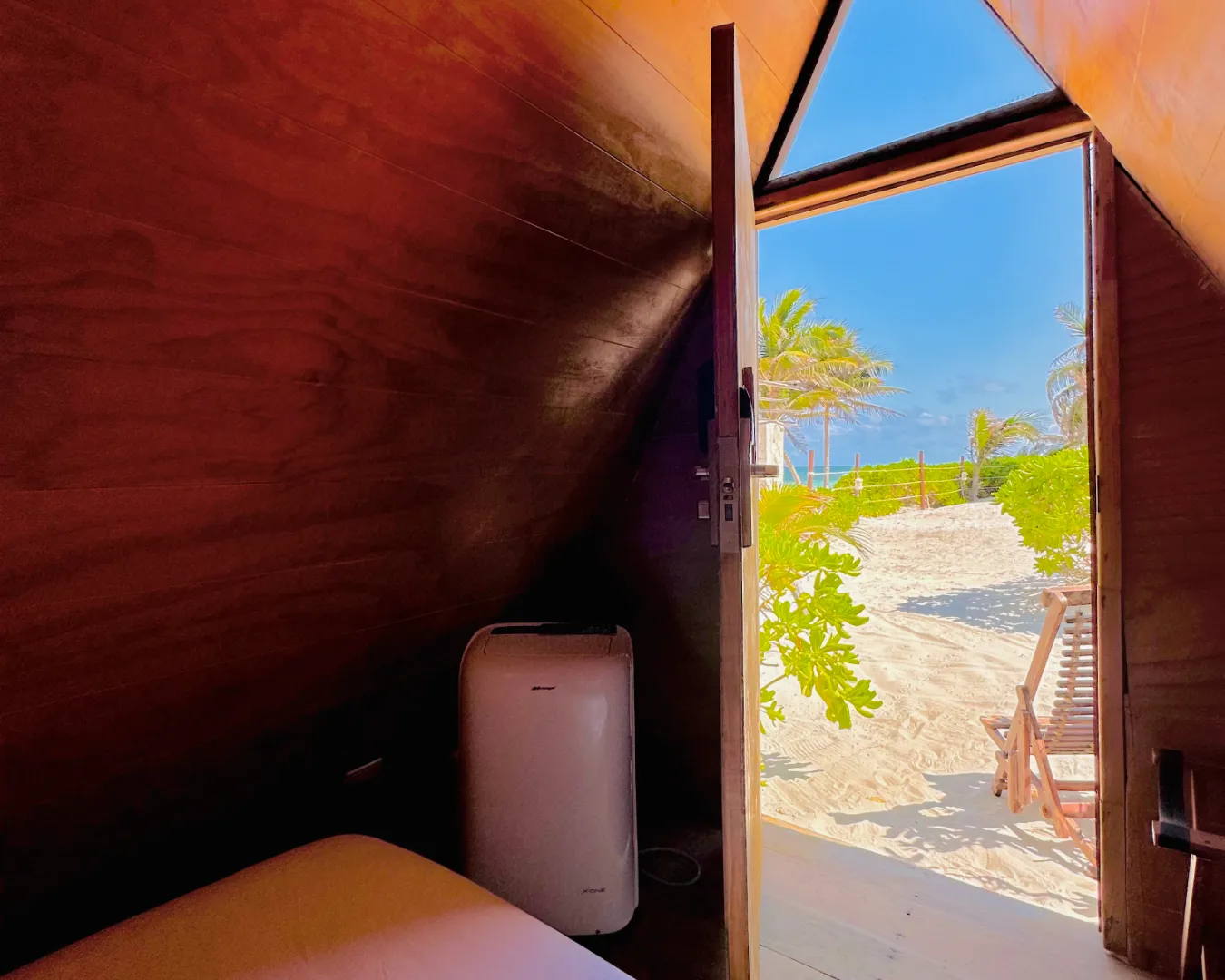 Vista de playa desde el interior de una cabaña de madera.