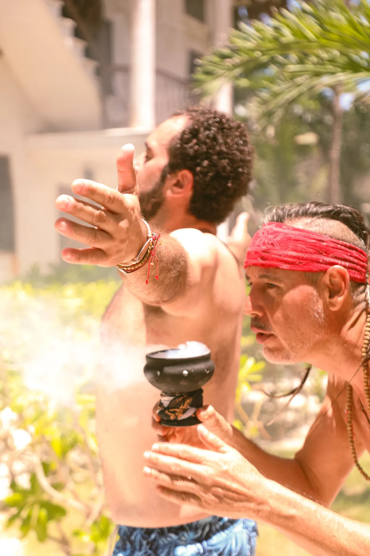 Hombre con incienso realiza ritual al aire libre en un entorno tropical.