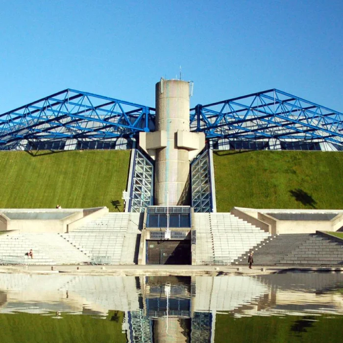 Bâtiment moderne avec structures bleu et vert réfléchies dans l'eau.