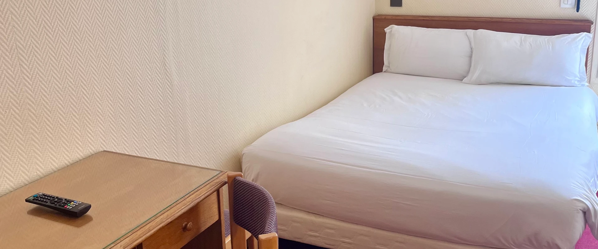 Petite chambre avec lit simple et bureau en bois.