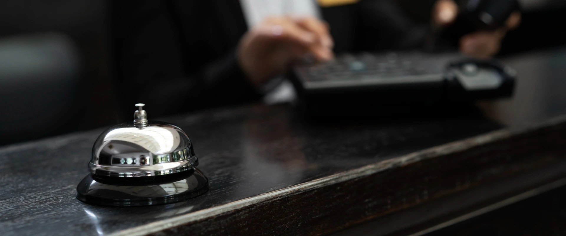 Cloche d'hôtel argentée sur un comptoir sombre.