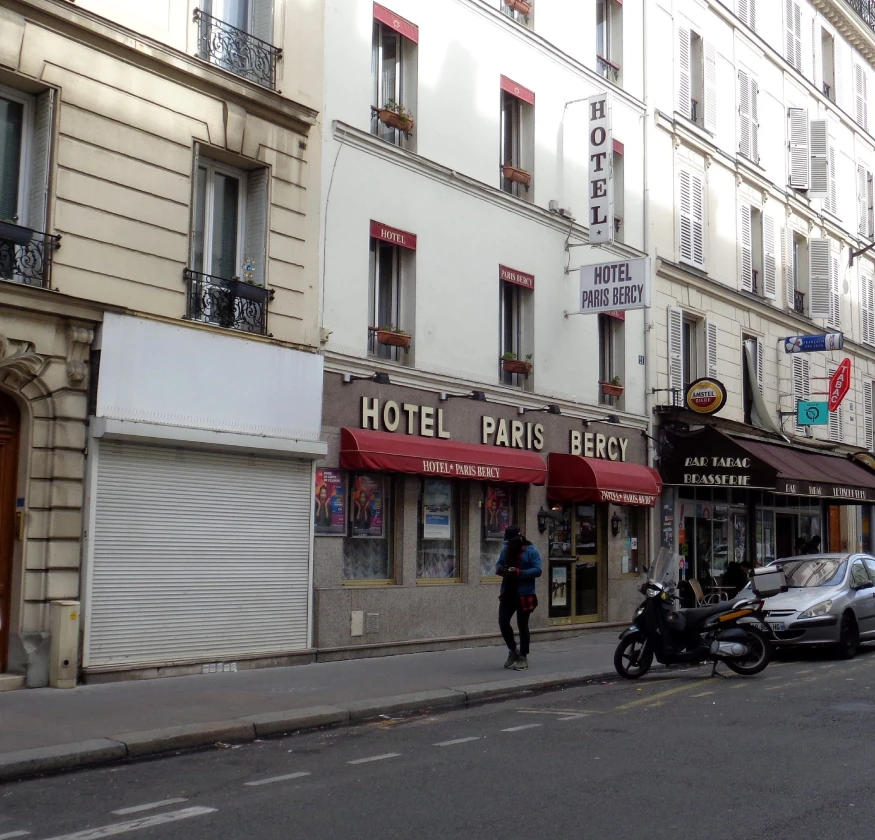 Façade de l'Hôtel Paris Bercy avec des auvents rouges sur une rue de Paris.