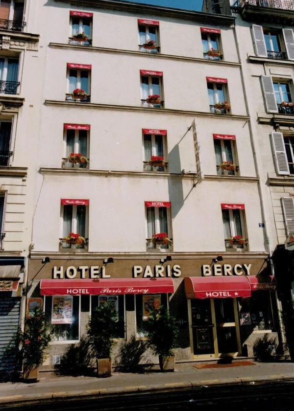 Façade d'un hôtel parisien avec auvents rouges et balcons fleuris.