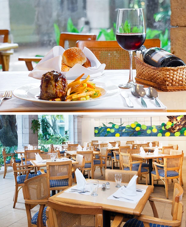 Plato de carne y vino en mesa de restaurante elegante, con comedor vac&iacute;o decorado con arte colorido y sillas de madera.