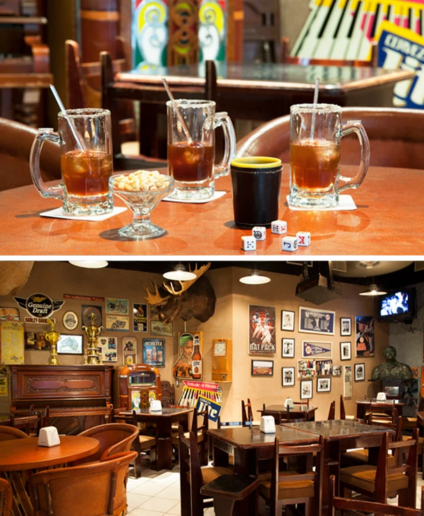 Tres cervezas en una mesa de bar con dados; fondo con decoraci&oacute;n retro y cuadros en las paredes.