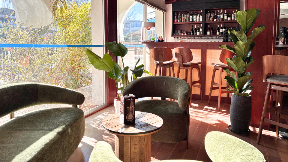 Espace bar de l'h&ocirc;tel avec canap&eacute;s, tables hautes et tabourets pour profiter d'un moment calme en d&eacute;couvrant notre s&eacute;lection de boissons ou notre carte snacking