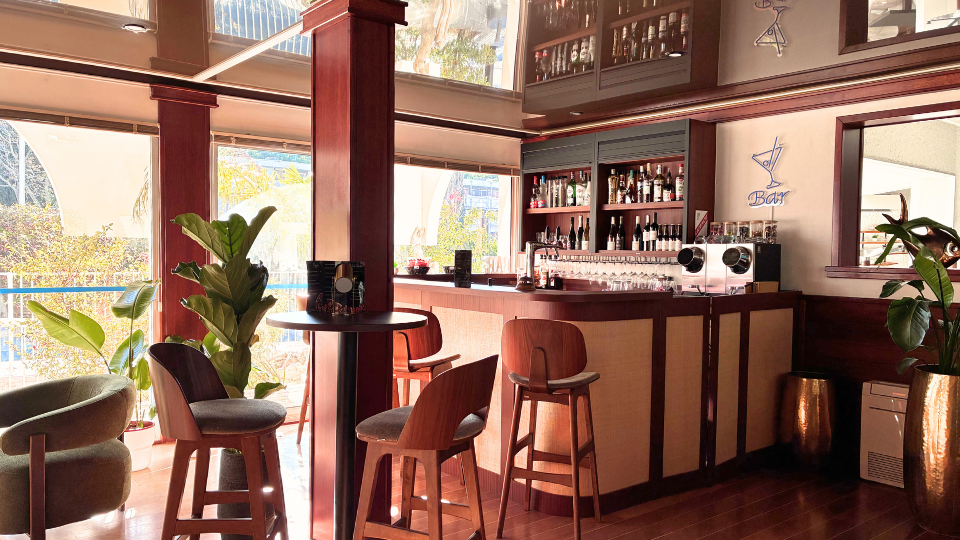 Espace bar de l'h&ocirc;tel avec canap&eacute;s, tables hautes et tabourets pour profiter d'un moment calme en d&eacute;couvrant notre s&eacute;lection de boissons ou notre carte snacking