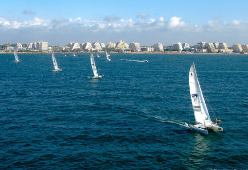 Voiliers naviguant sur la mer avec des immeubles en arri&egrave;re-plan.