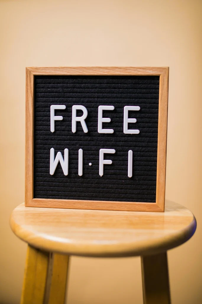 Panneau dans un cadre en bois pos&eacute; sur un banc, avec le texte en lettres blanches : &laquo; FREE WI-FI &raquo;.