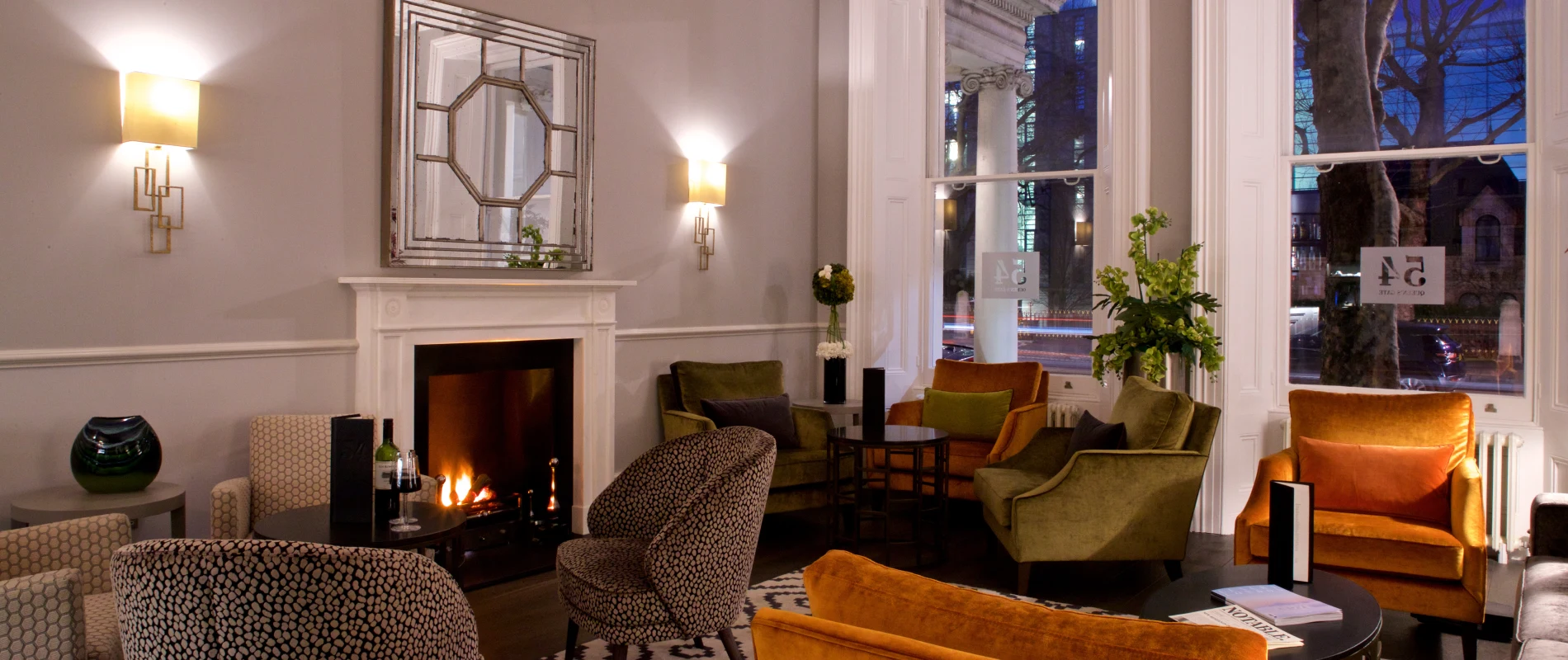 Cozy lounge with a fireplace, chairs, and a large window.