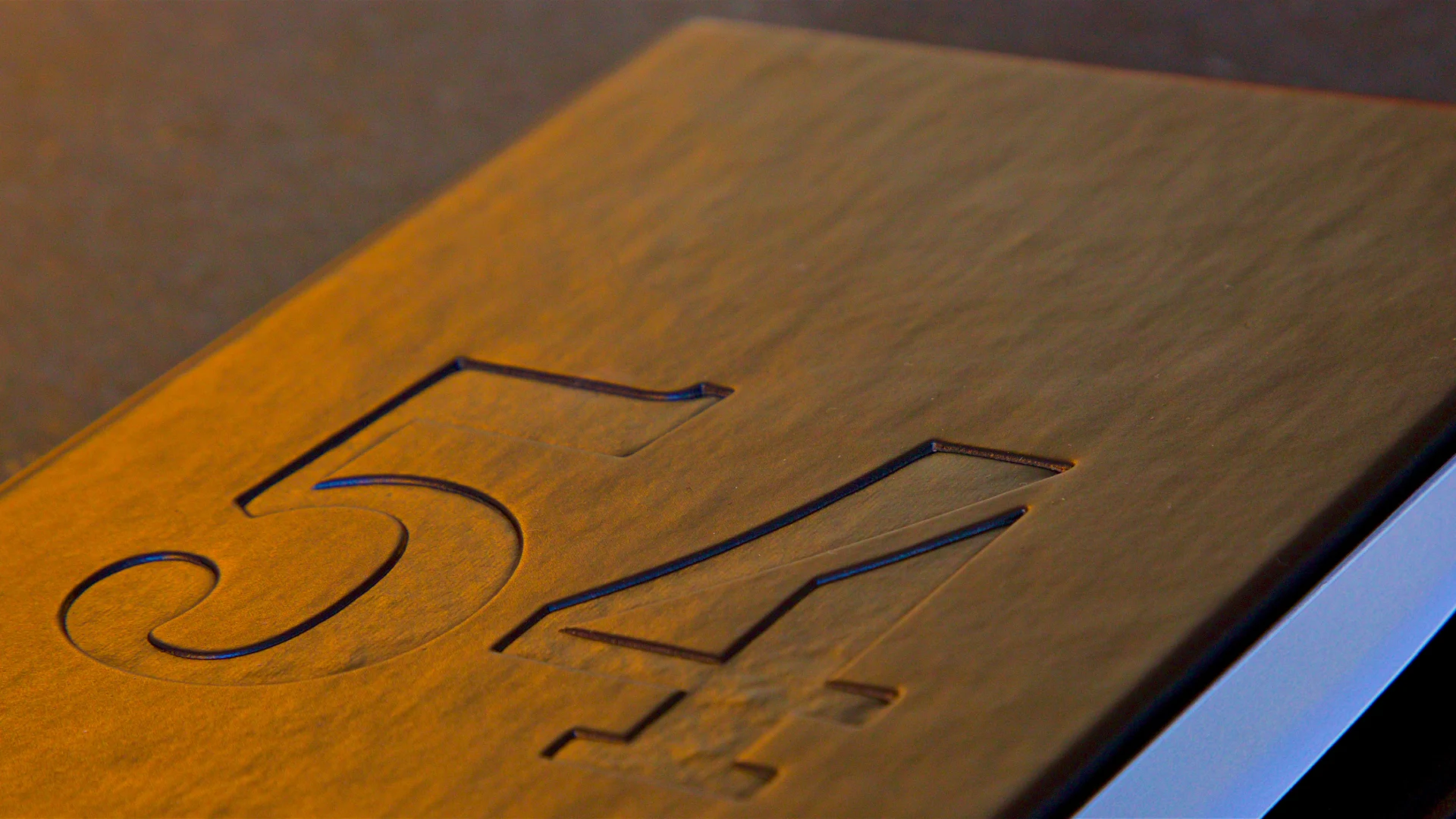 Number 54 engraved on a wooden surface, angled view.