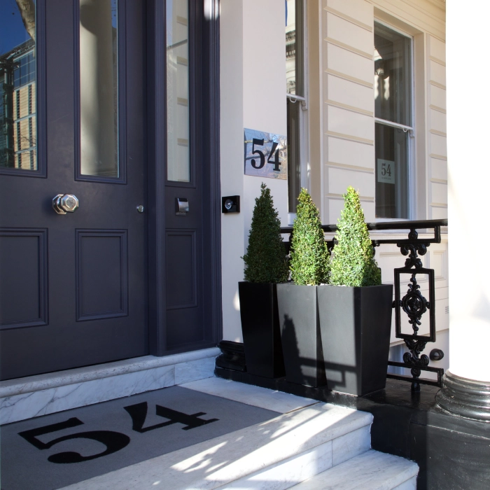 Doorway with potted plants and the number 54 on wall and doormat.