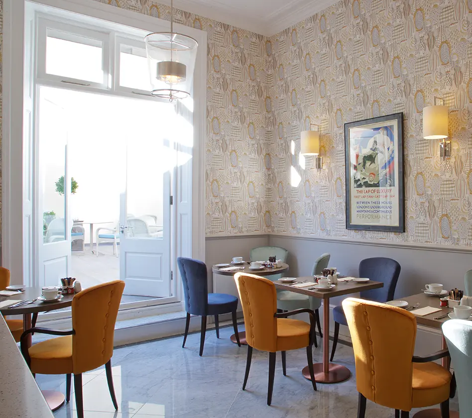 Stylish cafe with colorful chairs and elegant wallpaper.