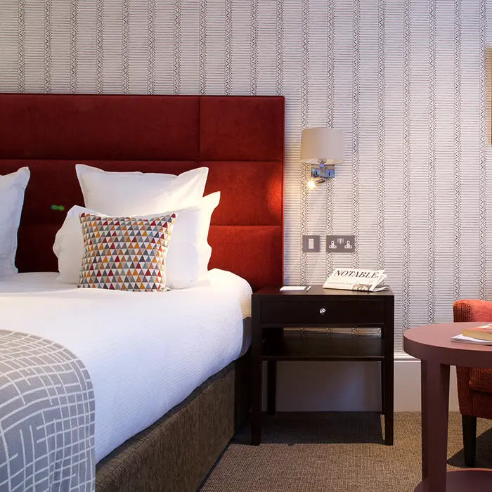 Cozy hotel room with a red headboard and geometric pillow.
