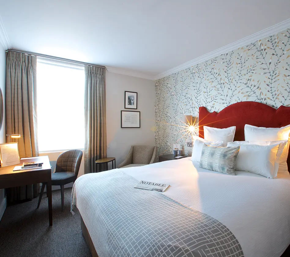 Cozy hotel room with a red headboard and patterned wallpaper.