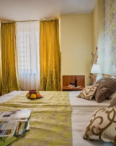 Cozy bedroom with yellow curtains, decorative pillows, and fruit on the bed.