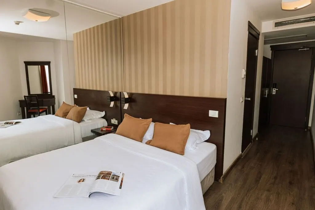 Hotel room with a bed, pillows, a magazine, and a mirror.