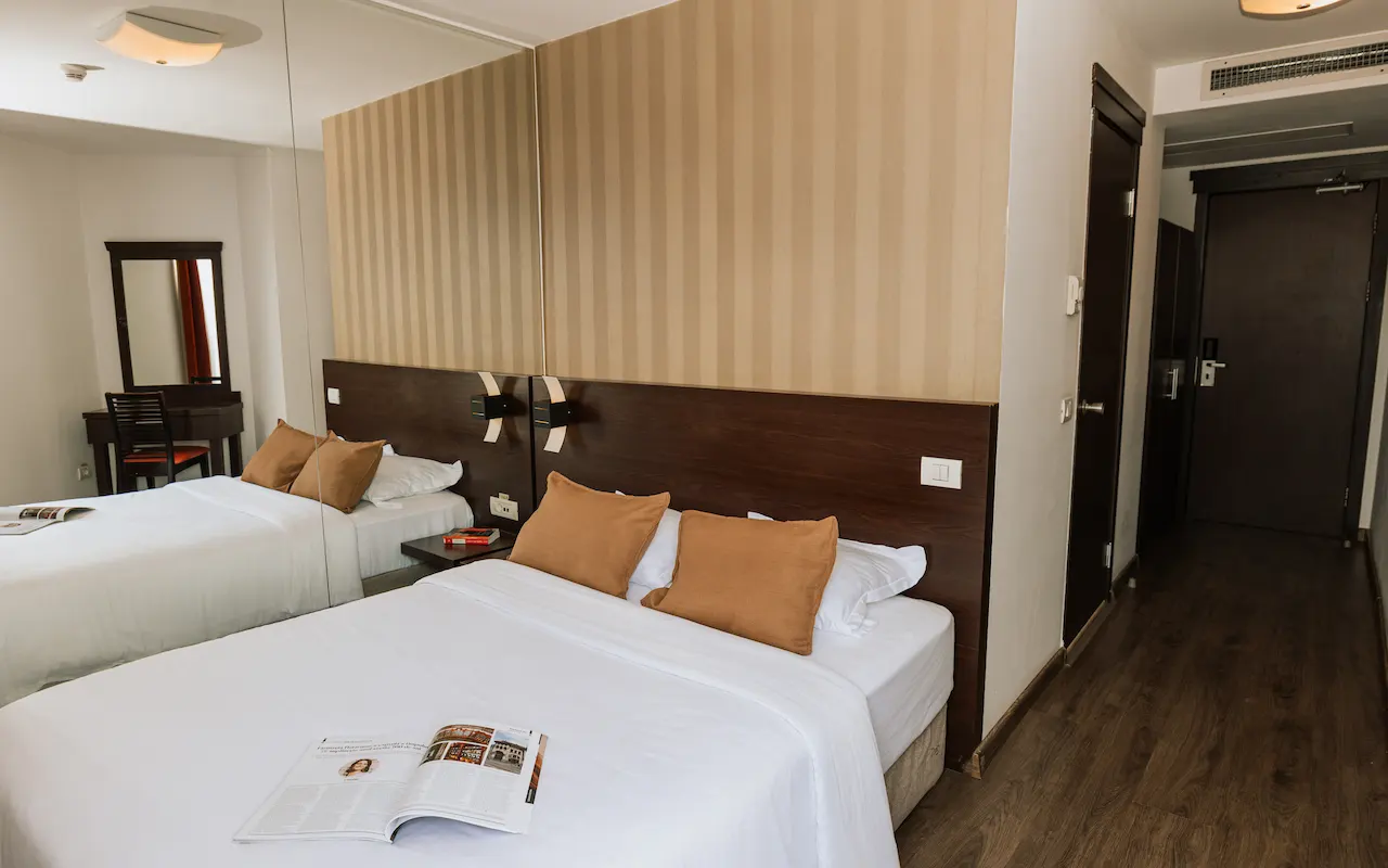 Hotel room with a bed, pillows, and a magazine on the blanket.