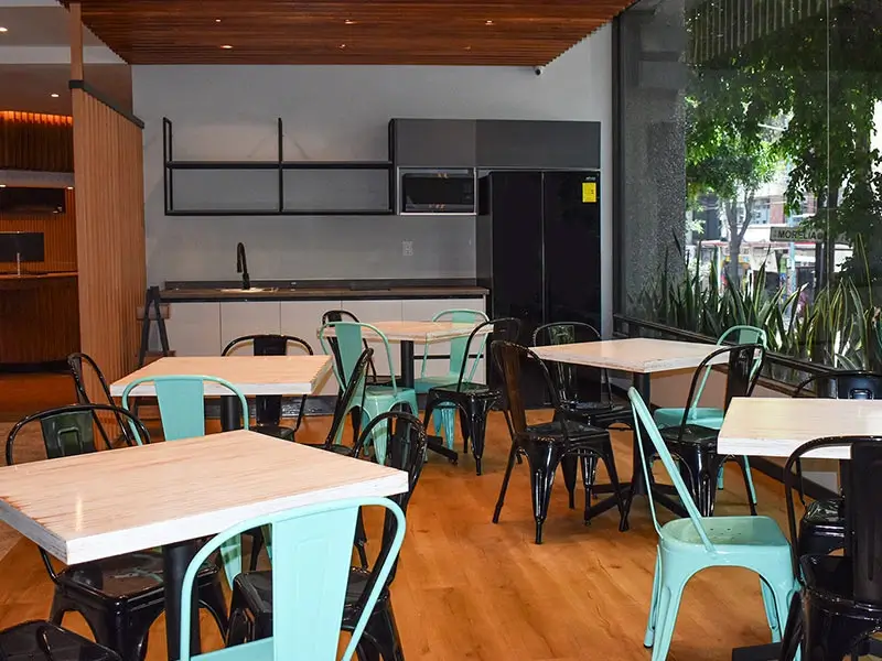 Comedor moderno con mesas blancas y sillas negras y turquesas.