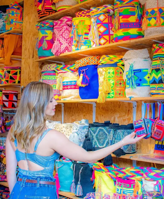 Mujer eligiendo coloridas mochilas artesanales en una tienda de souvenirs.