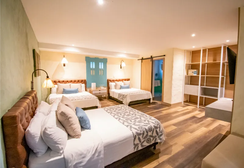 Habitaci&oacute;n doble moderna con camas grandes, lamparas c&aacute;lidas y decoraci&oacute;n acogedora.