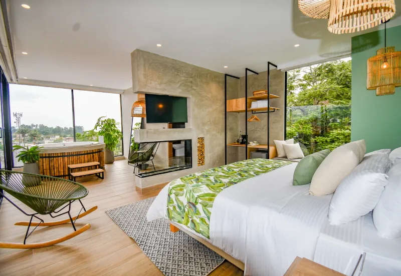 Dormitorio moderno con decoraci&oacute;n verde, vista al exterior y jacuzzi junto a la ventana.