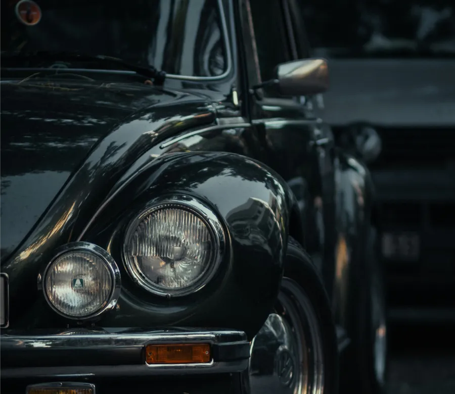Coche cl&aacute;sico negro con faros redondos y reflejos en la carrocer&iacute;a.