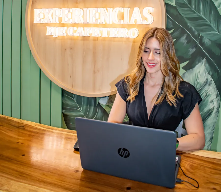 Mujer sonriente trabajando en una laptop HP, con fondo de hojas y letrero de "Experiencias".