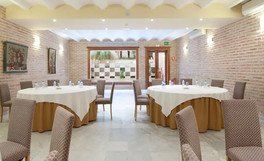 Sala de reuniones con mesas redondas y sillas, decoraci&oacute;n elegante y luz natural.