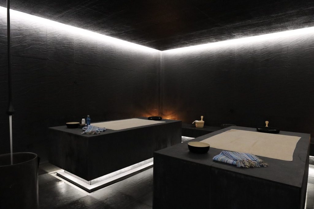 Dark room with two massage tables, dim lighting, and towels.