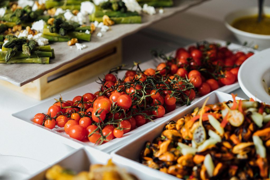 Cherry tomatoes, asparagus, and salads are arranged on a table.