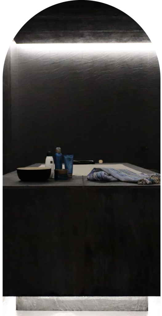 Dimly lit bathroom with toiletries and towels on a counter.