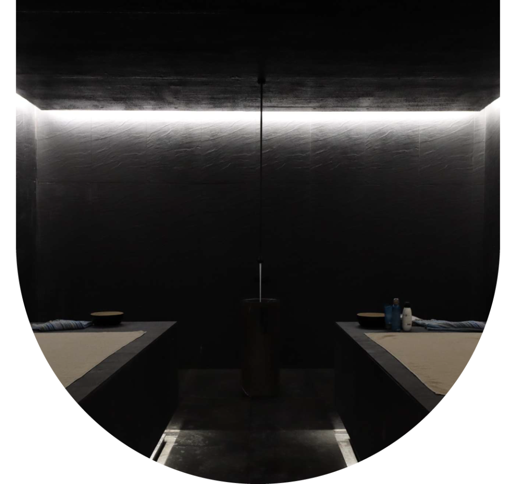 Dimly lit spa room with two massage tables and a centered light fixture.