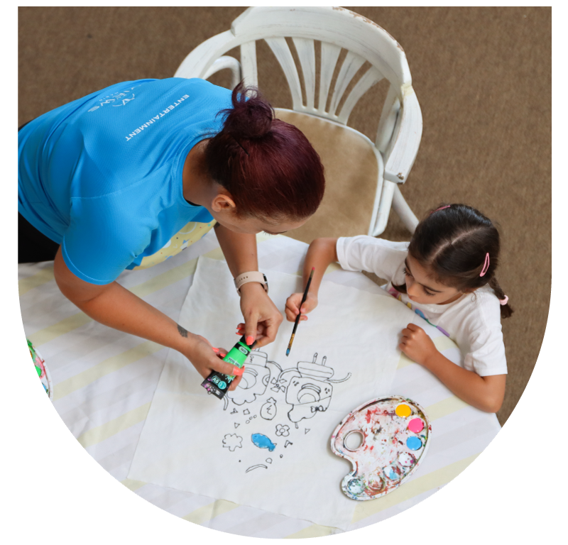 Children painting on fabric with brushes and colorful paints.