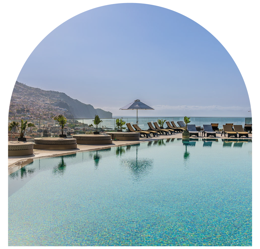 Rooftop pool with lounge chairs, mountain view, and clear blue sky.