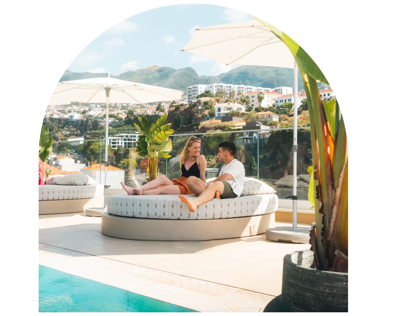 Couple relaxing on a poolside sunbed with scenic mountain view in the background.