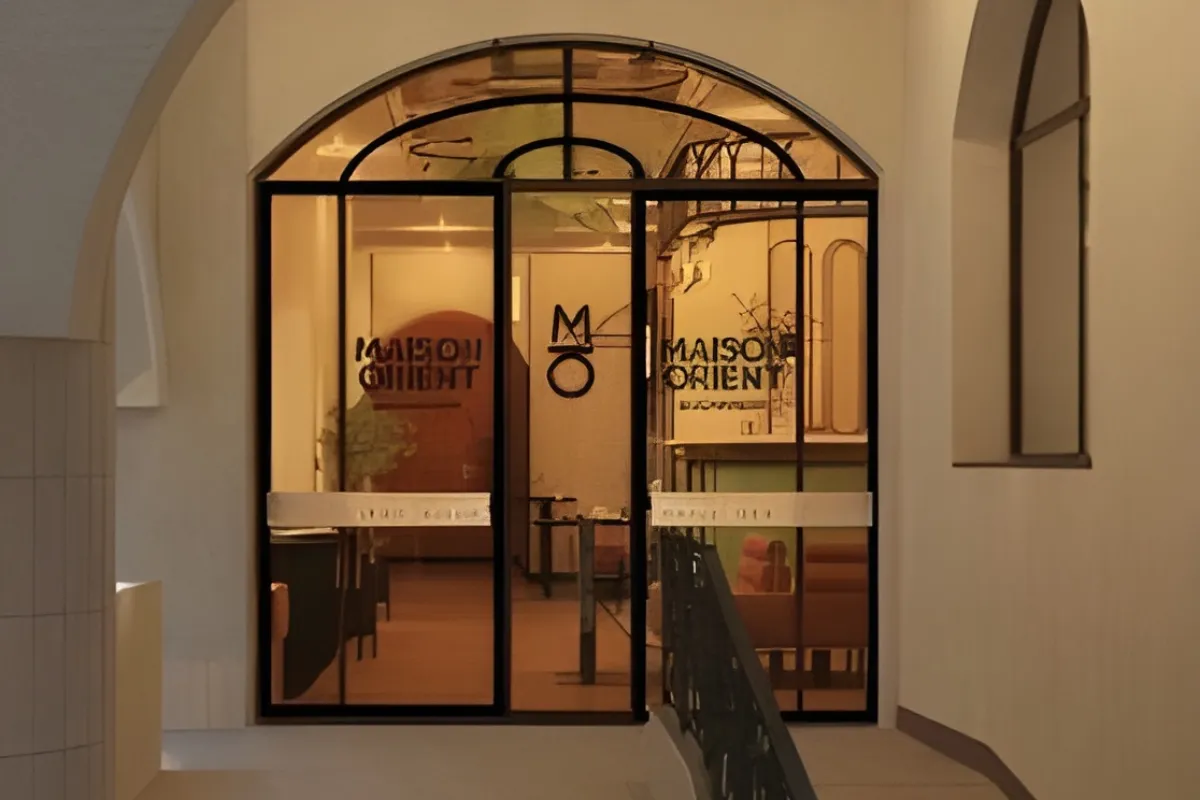 Glass doors of "Maison Orient" with warm interior lighting.