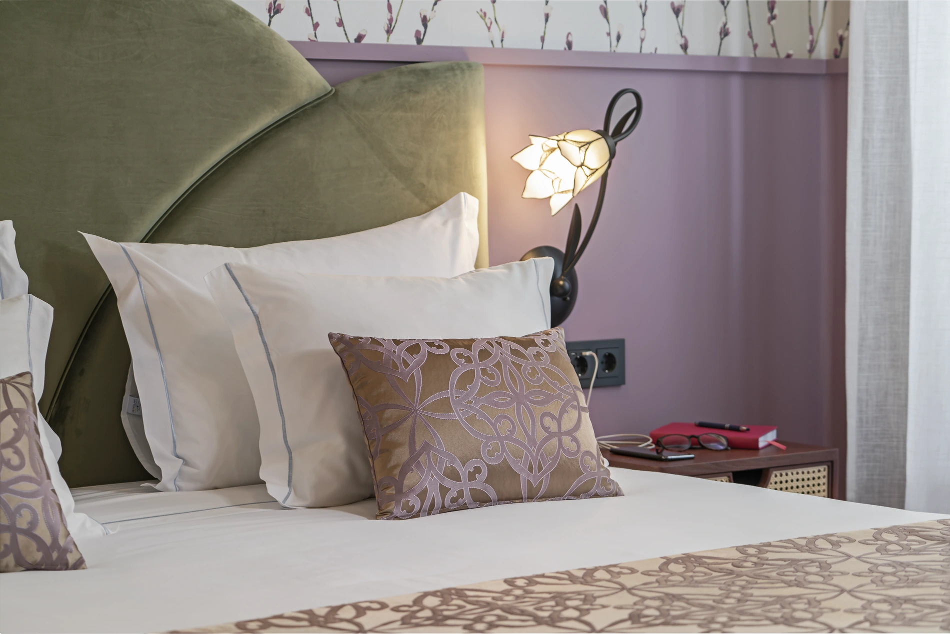 Cozy bed with patterned pillows and a decorative lamp in a stylish room.