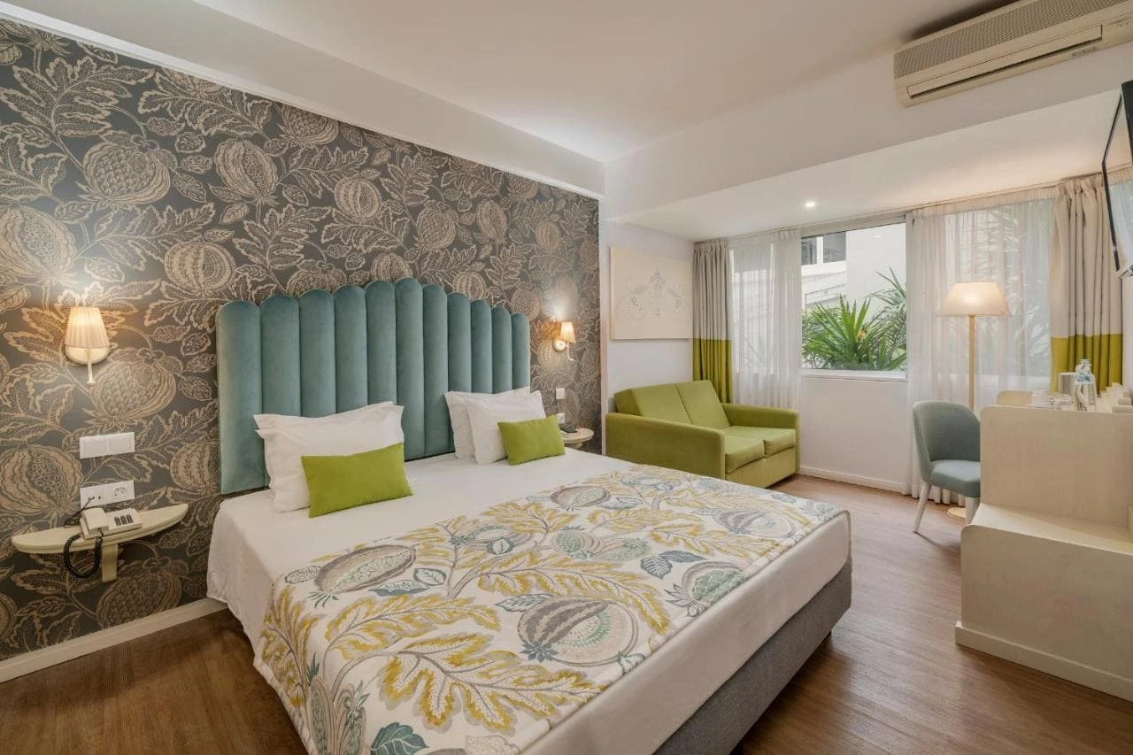 Hotel room with a patterned bed, green sofa, and stylish decor.