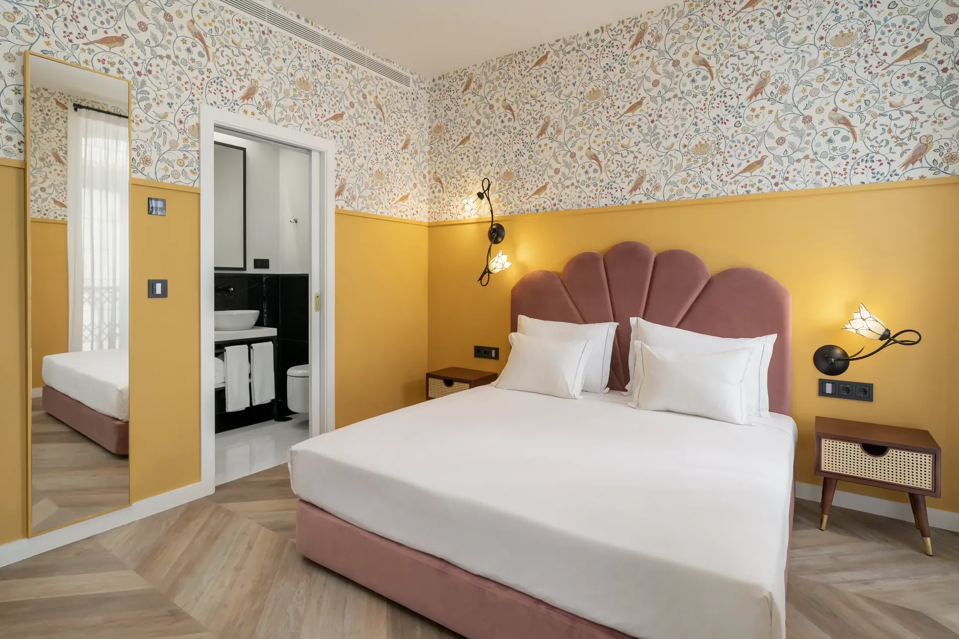 Stylish bedroom with floral wallpaper and pink headboard.