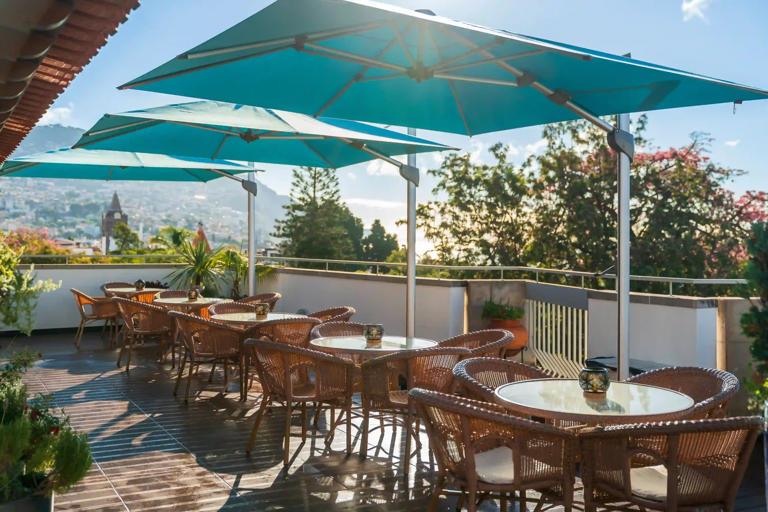 Rooftop cafe with blue umbrellas and wicker chairs on a sunny day.