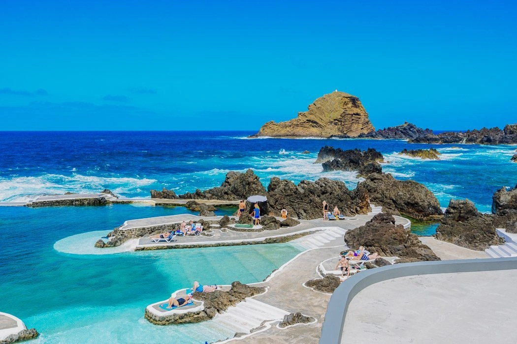 Natural pools with rocky formations and ocean view under a clear blue sky.