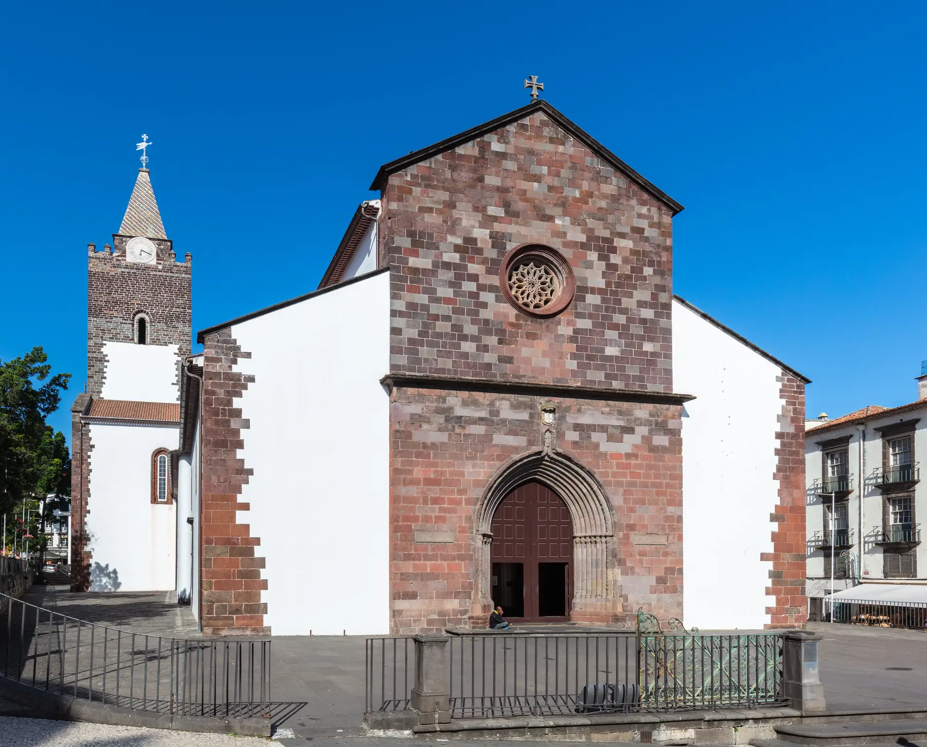 A church with a brick facade and bell tower under a blue sky.