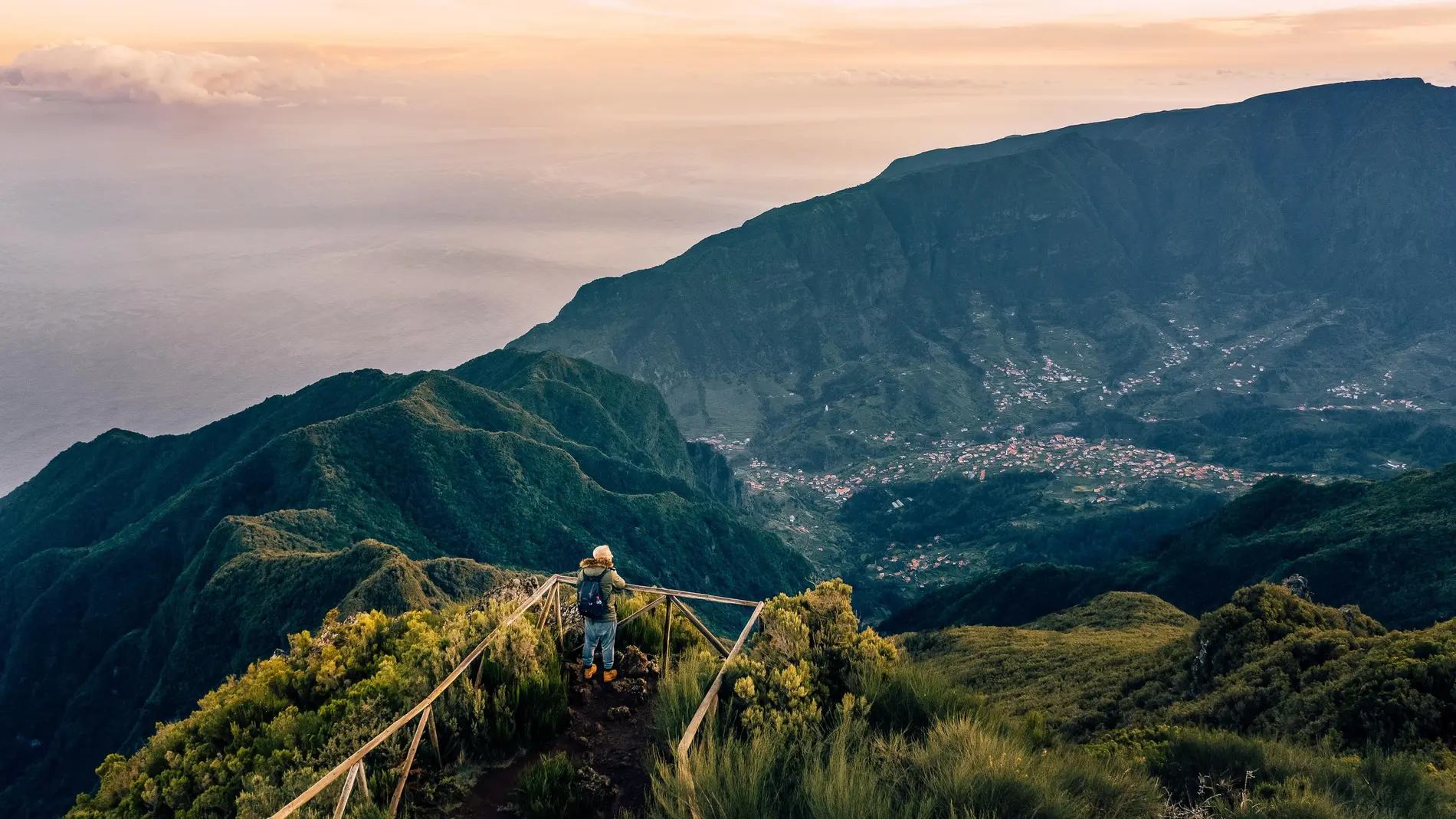 Hiker overlooking scenic mountain view at sunrise.